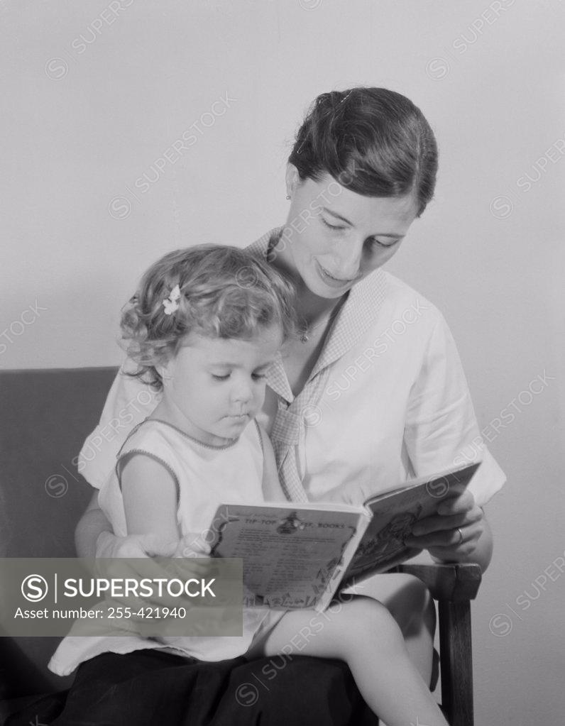 Stock Photo: 255-421940 Mother reading book to daughter