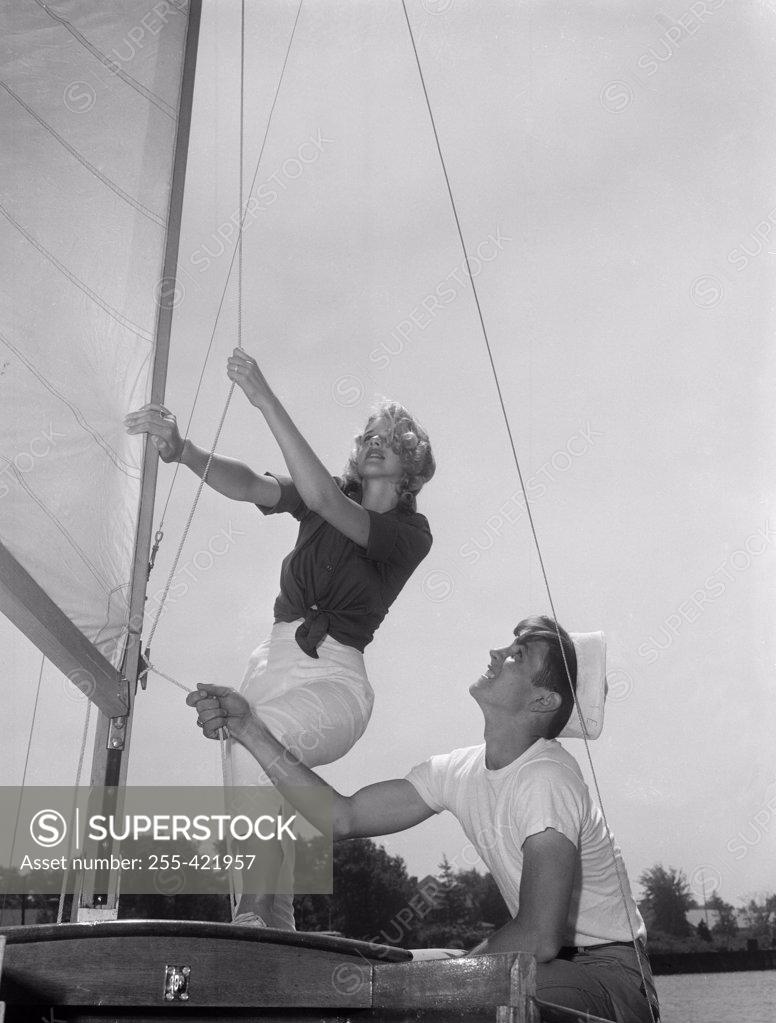 Stock Photo: 255-421957 Couple on yacht deck adjusting sail