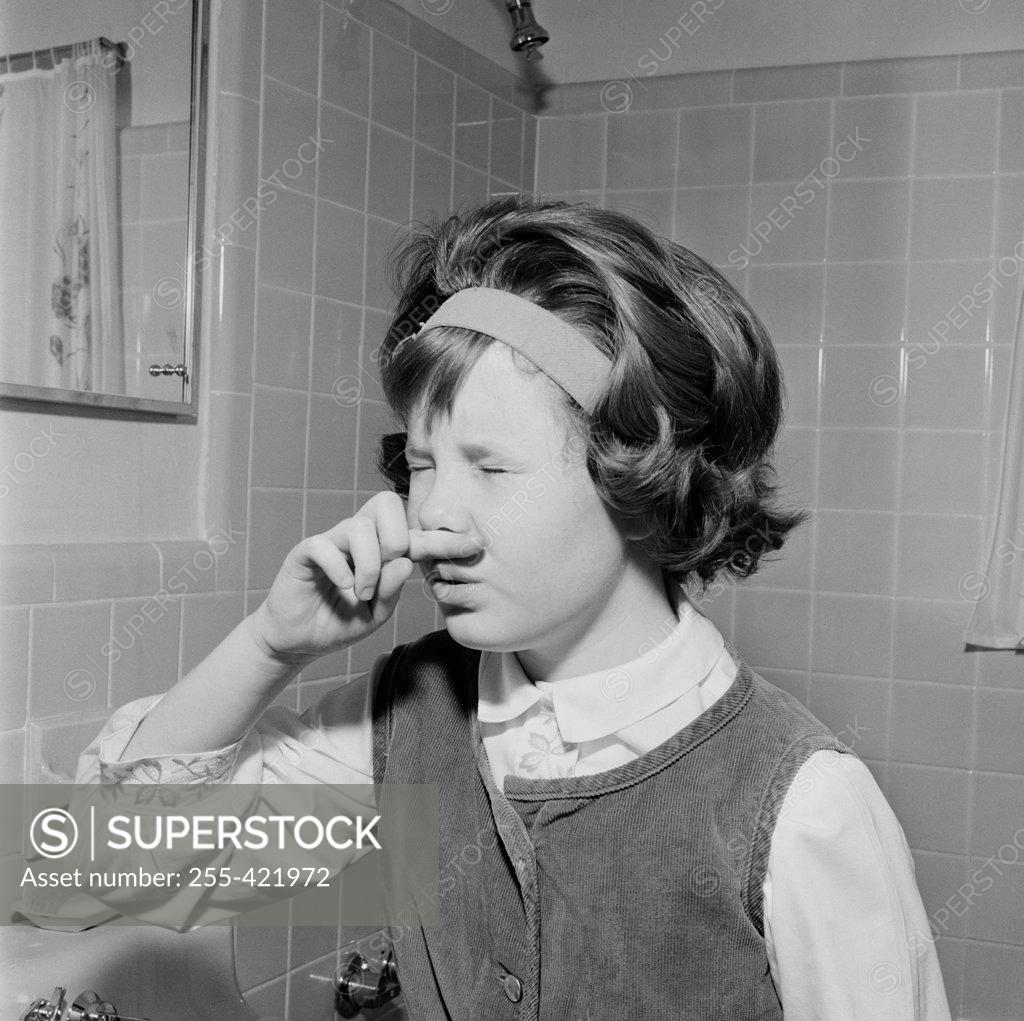 Stock Photo: 255-421972 Young girl grimacing in front of bathroom mirror