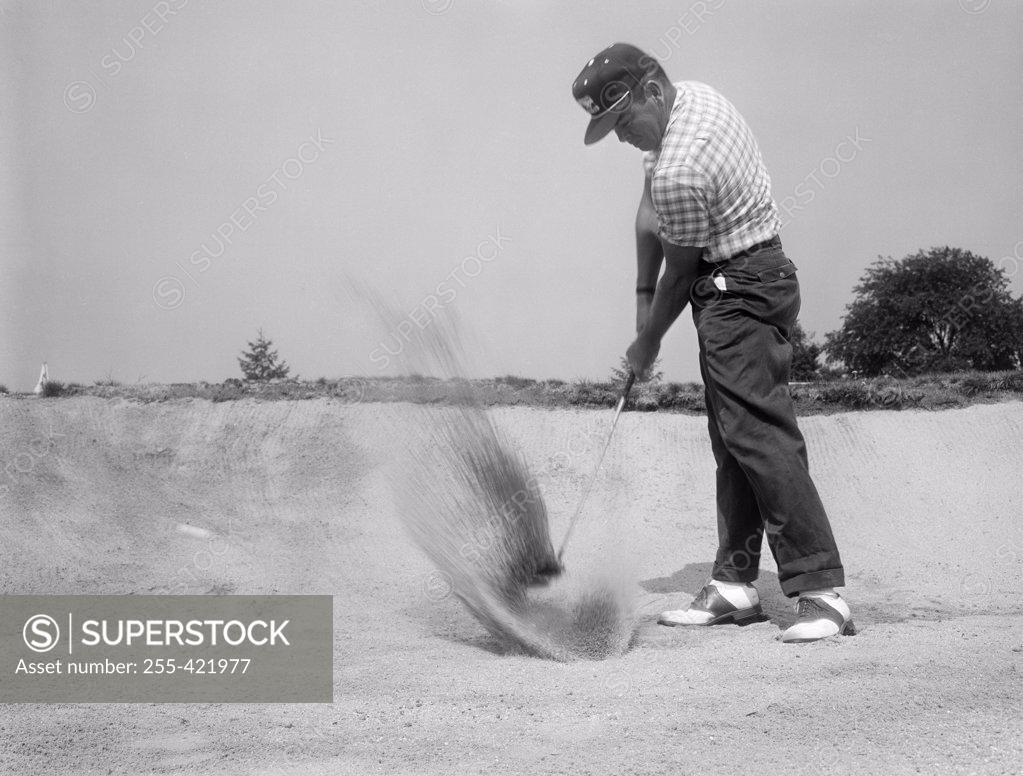 Stock Photo: 255-421977 Mature man playing golf on sandy course