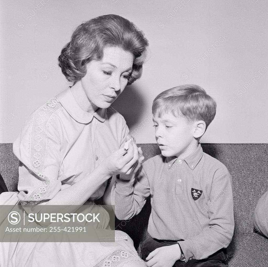 Stock Photo: 255-421991 Young woman cutting boy's nails