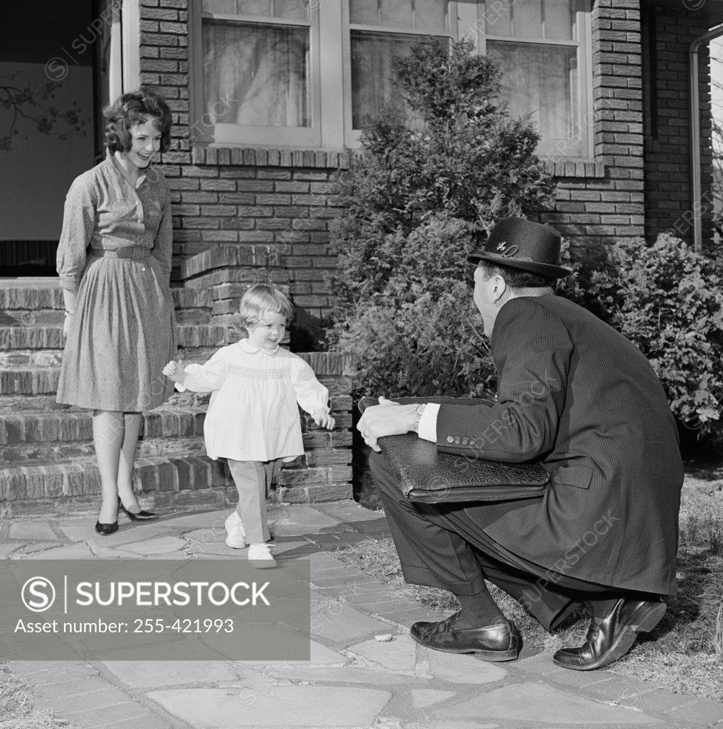 Stock Photo: 255-421993 Businessman saying hello to wife and young daughter as he comes back from work
