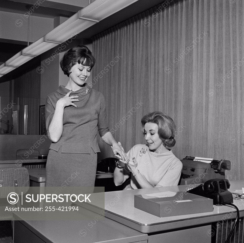 Stock Photo: 255-421994 Secretary showing painted fingernails to colleague