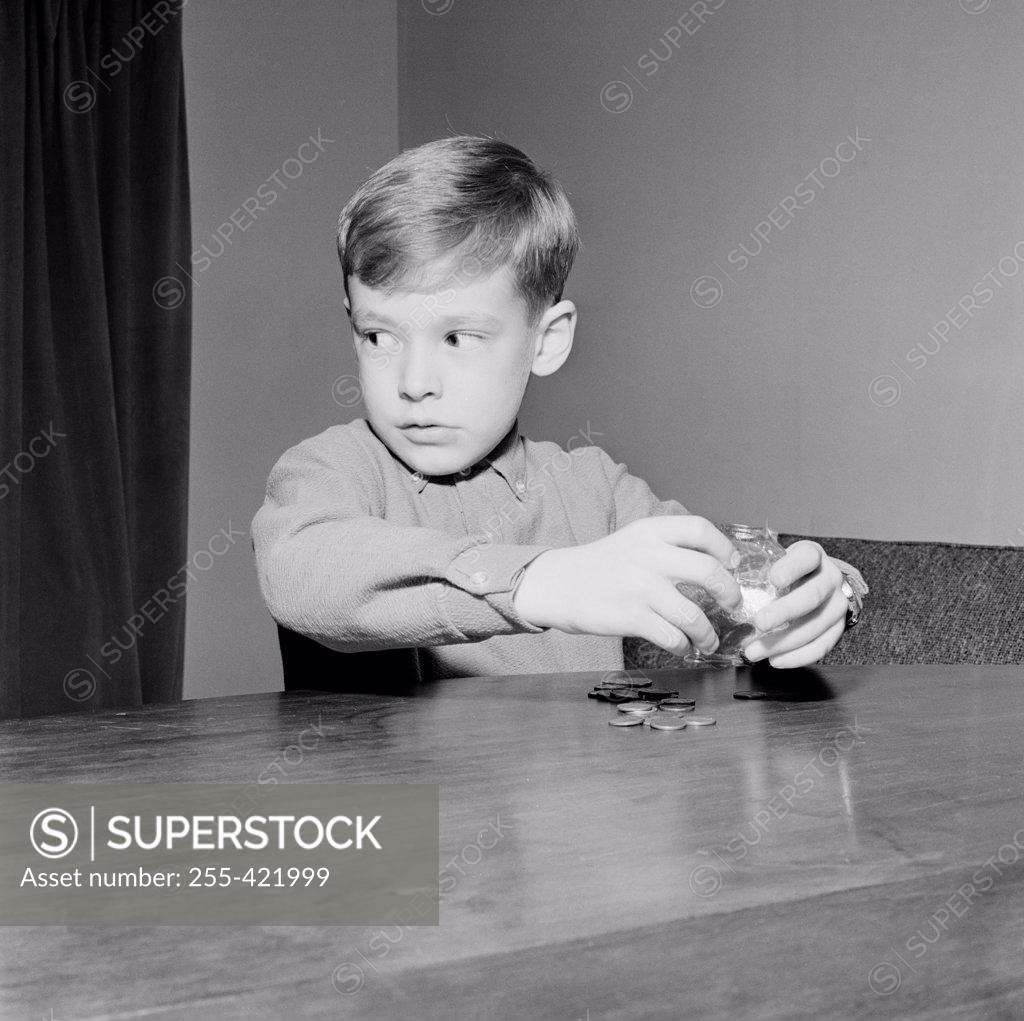 Stock Photo: 255-421999 Young boy putting coins in piggybank