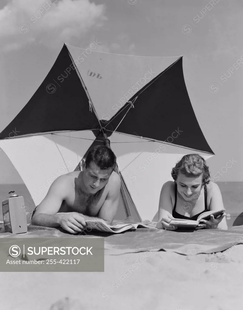 Young couple reading books on beach