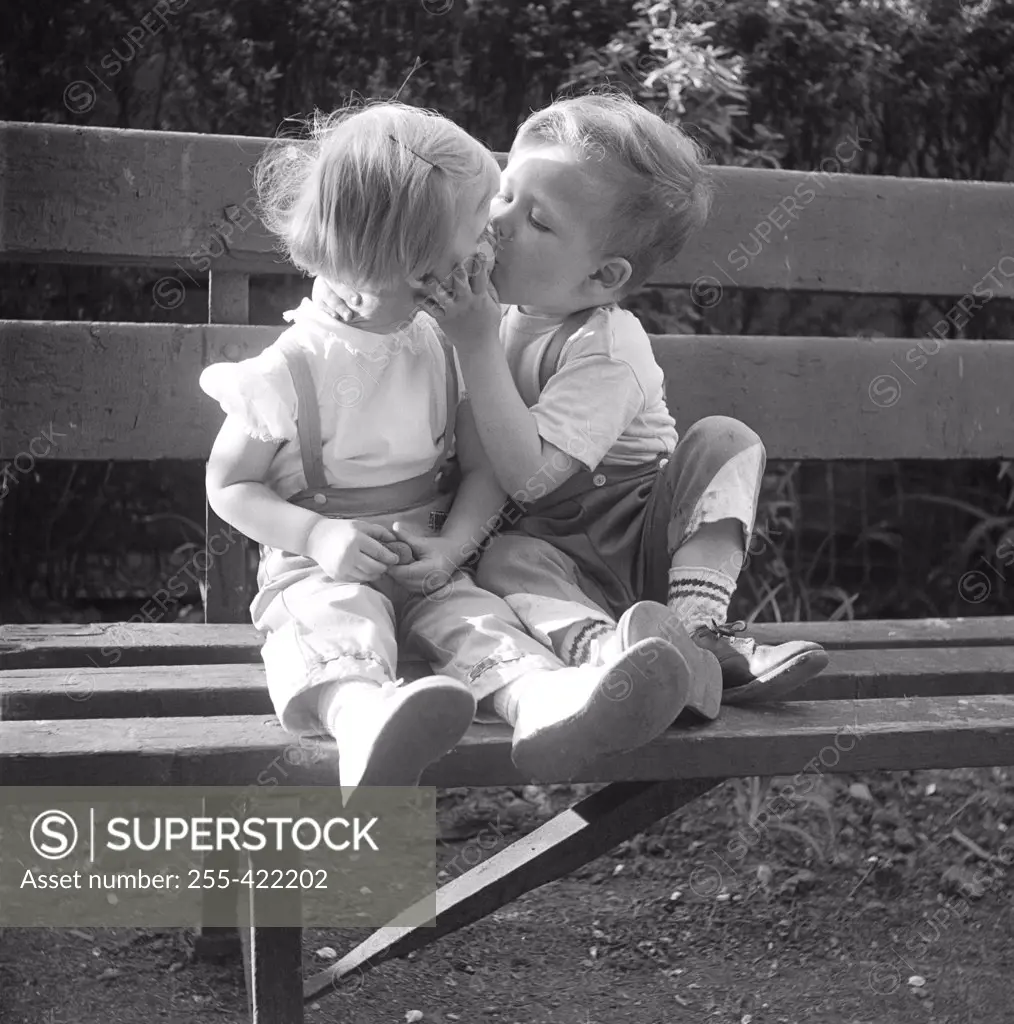 Boy and girl kissing on park bench