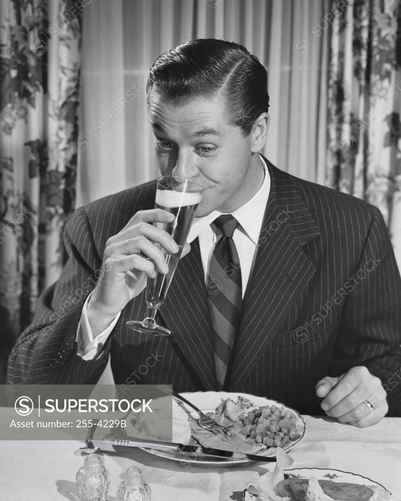 Stock Photo: 255-4229B Mid adult man sitting at table drinking beer