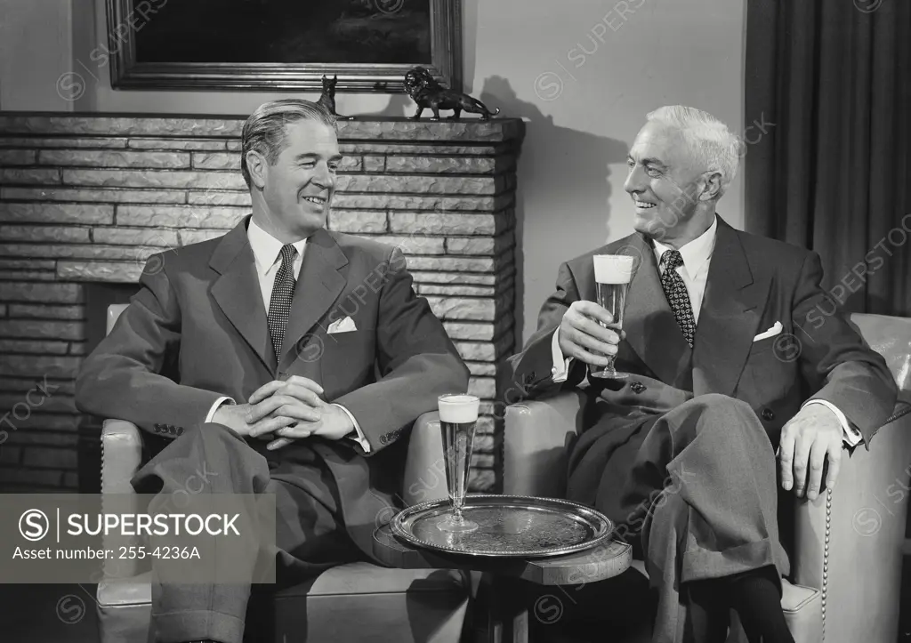 Close-up of two mature men sitting together and drinking beer