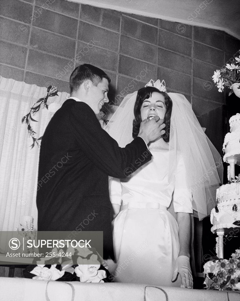 Stock Photo: 255-4244 Low angle view of a groom feeding a piece of cake to his bride