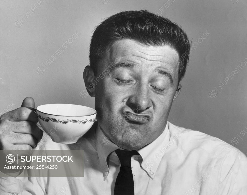 Stock Photo: 255-4250 Mature man holding tea cup and making a face