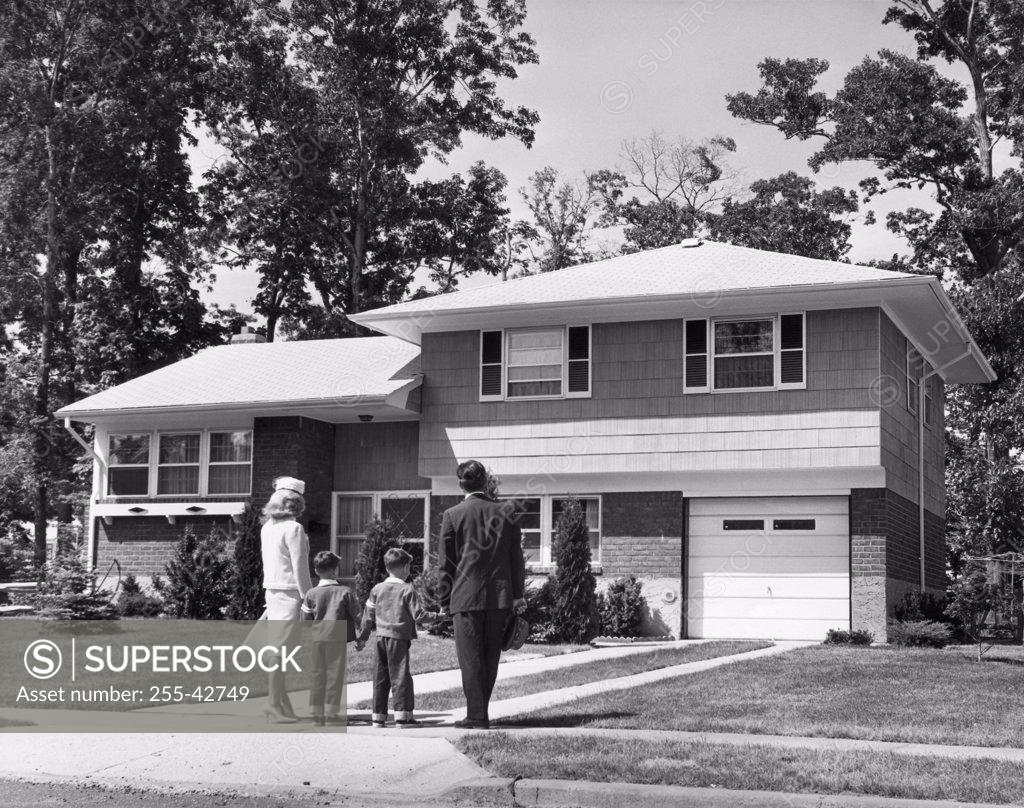 Stock Photo: 255-42749 Rear view of a mid adult couple standing with their two children in front of a house
