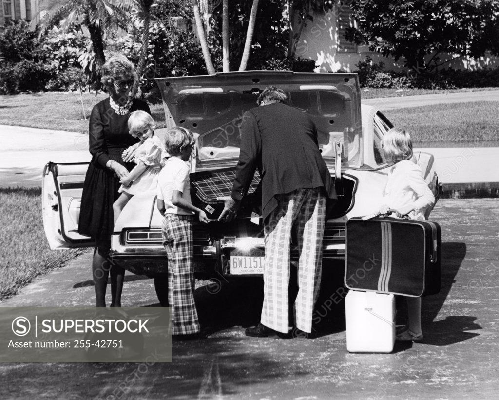 Stock Photo: 255-42751 Parents and their children loading luggage into a car