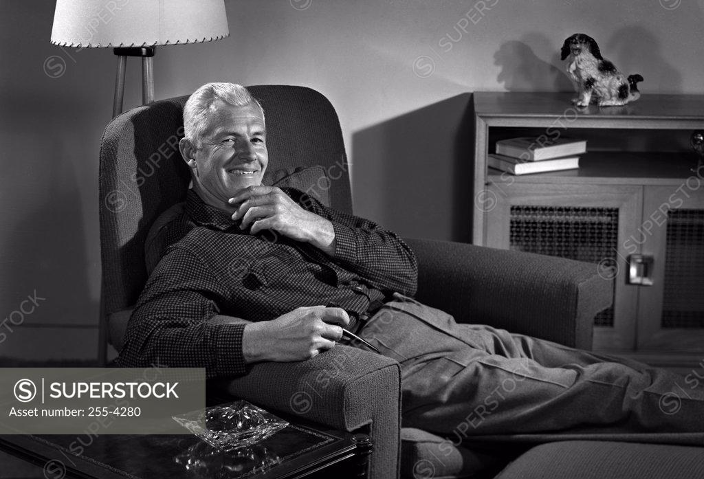 Stock Photo: 255-4280 Senior man holding pipe and lying in armchair, portrait