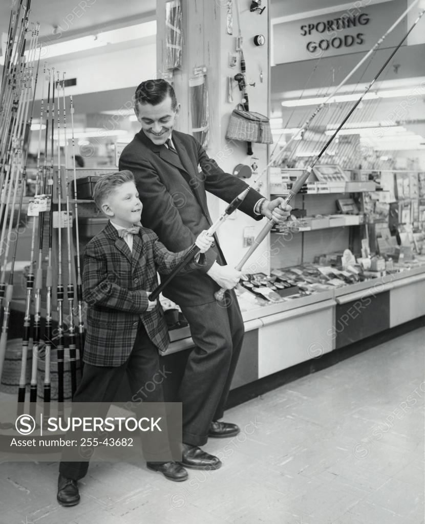 Stock Photo: 255-43682 Mature man and boy holding fishing rods in store
