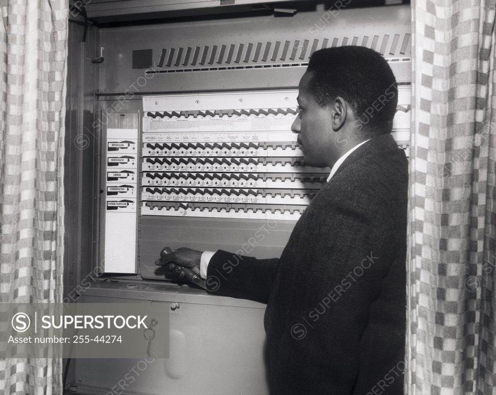 Stock Photo: 255-44274 Side profile of a senior man casting his vote in a voting booth