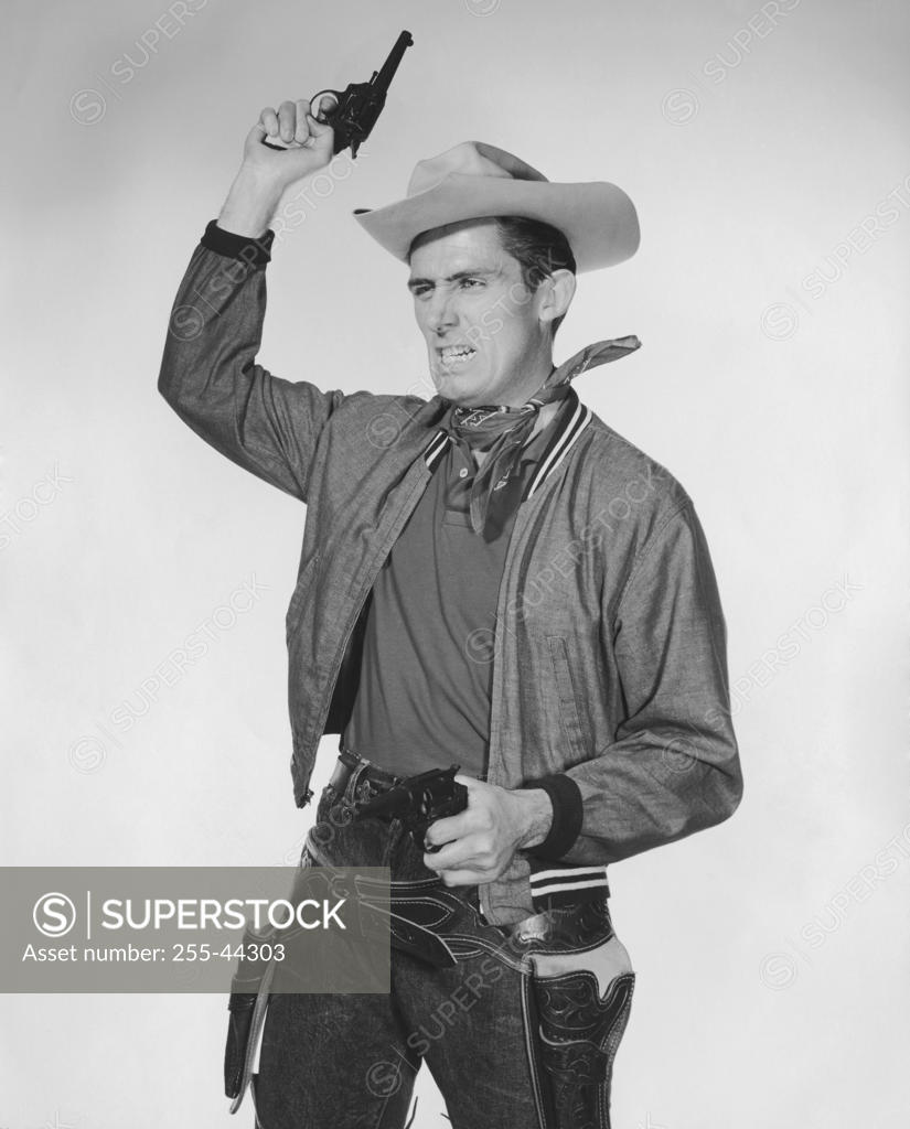 Stock Photo: 255-44303 Portrait of cowboy shooting into the air and pointing handgun