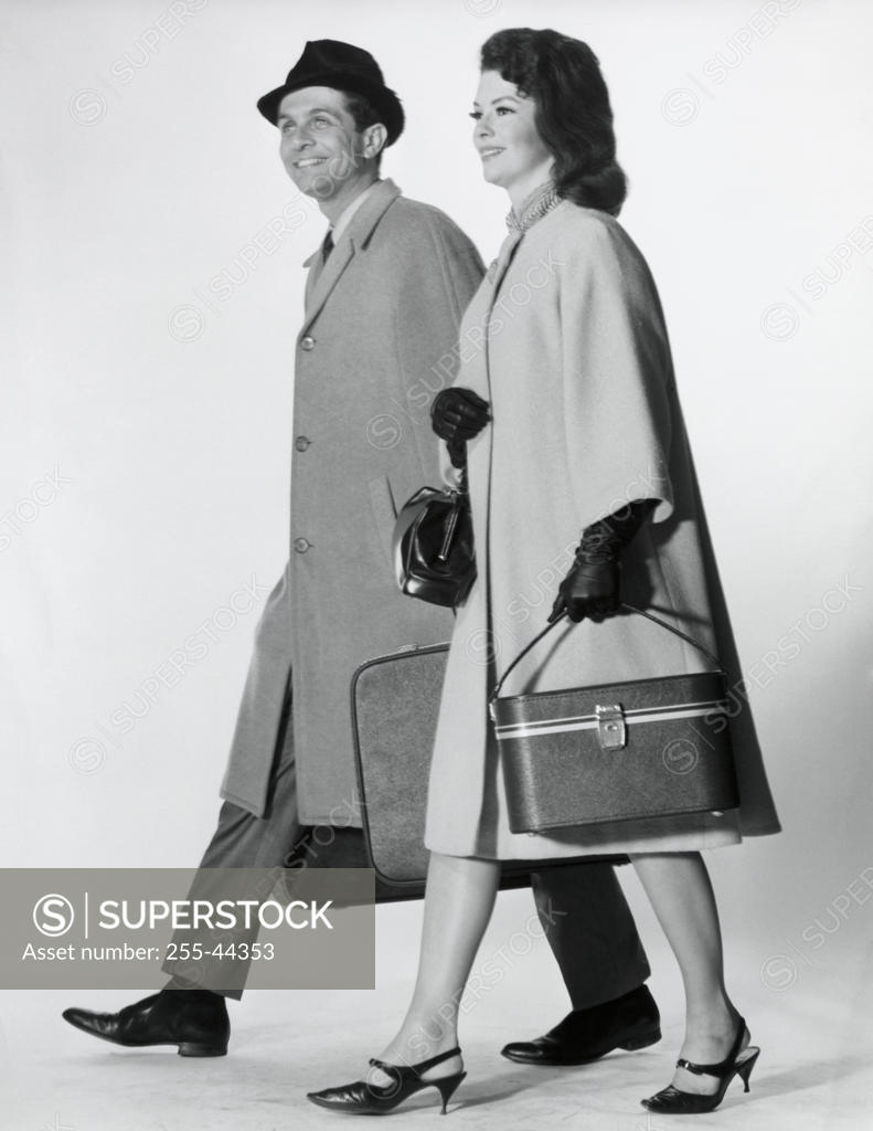 Stock Photo: 255-44353 Side profile of a mid adult couple walking with luggage