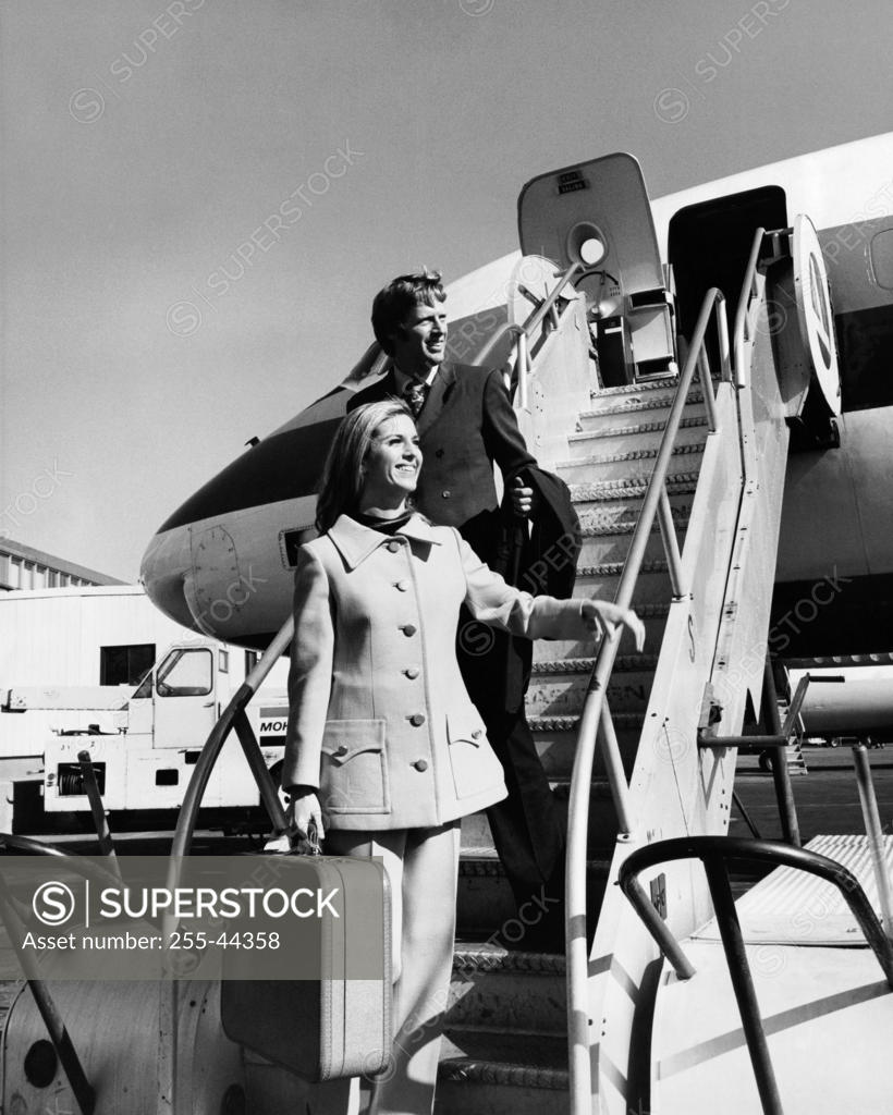 Stock Photo: 255-44358 Young woman with a young man standing on a staircase of an airplane