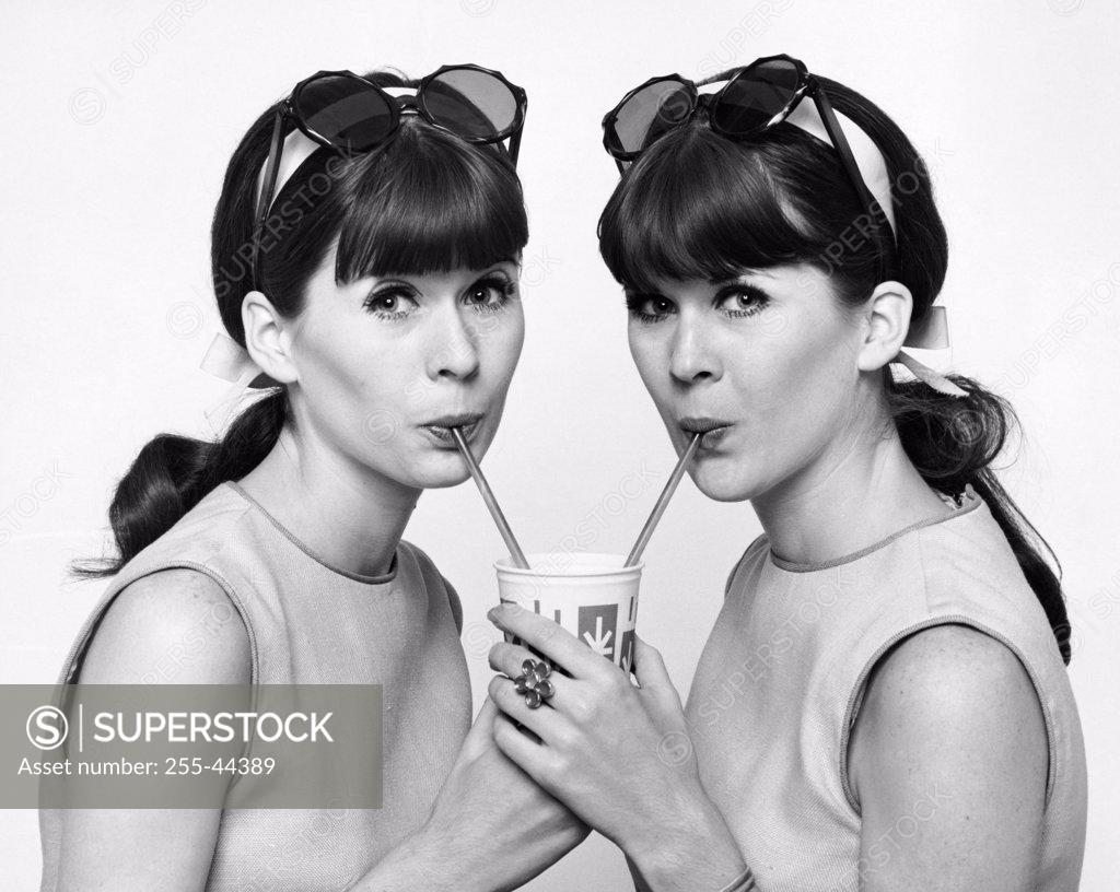 Stock Photo: 255-44389 Portrait of twin young women drinking cold drink
