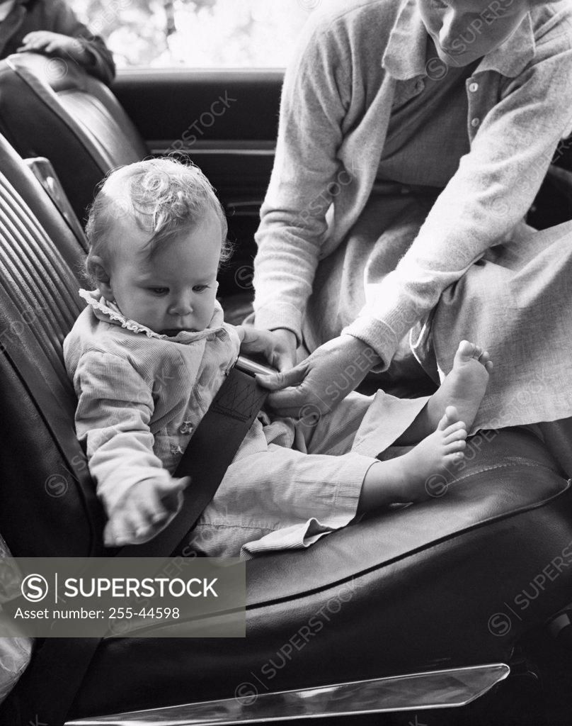 Stock Photo: 255-44598 Mid adult woman fastening her daughter's car seat belt