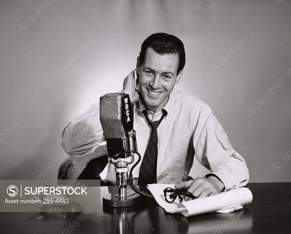 Portrait of a mid adult man sitting in front of a microphone in a radio station