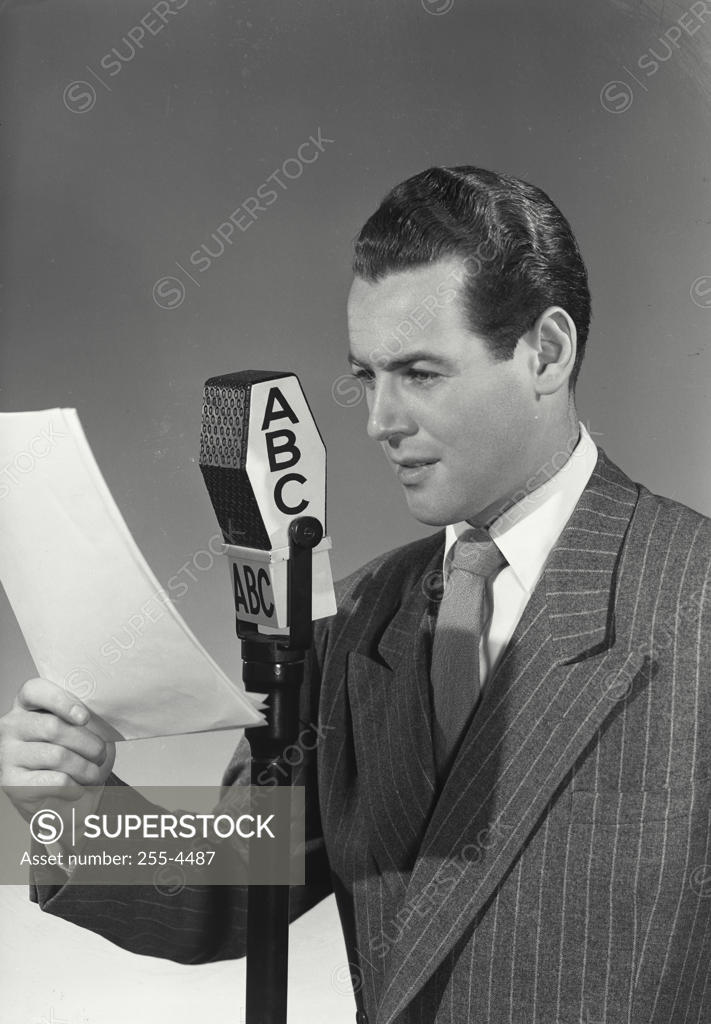 Stock Photo: 255-4487 Mid adult man reading a report into a microphone