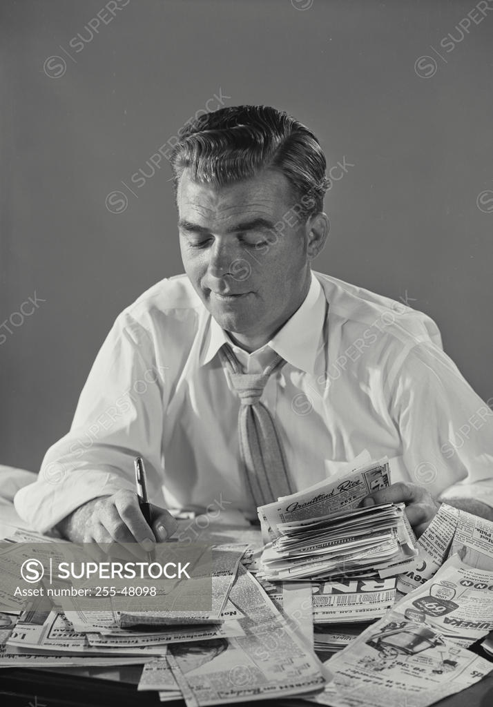 Stock Photo: 255-48098 Close-up of a businessman writing on newspaper cuttings