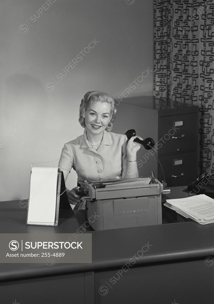 Stock Photo: 255-4889 Portrait of a businesswoman holding a telephone receiver and smiling, 1954