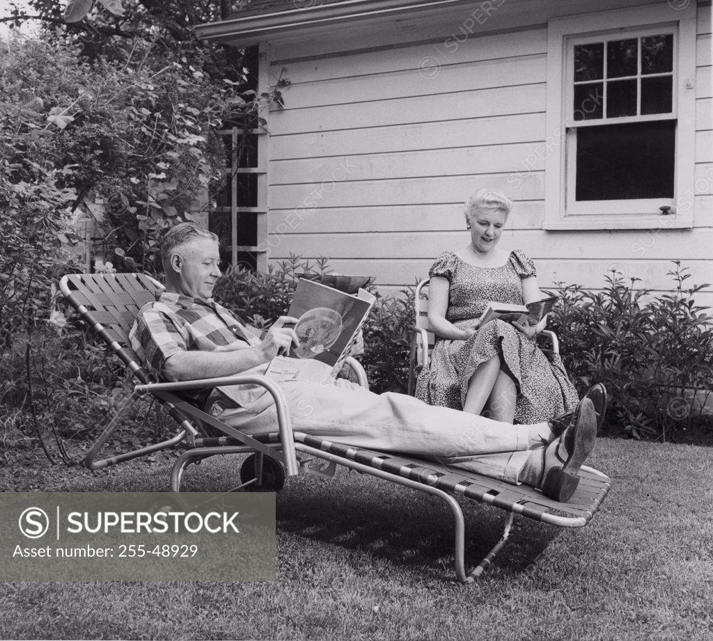 Stock Photo: 255-48929 Senior couple reading books in the backyard