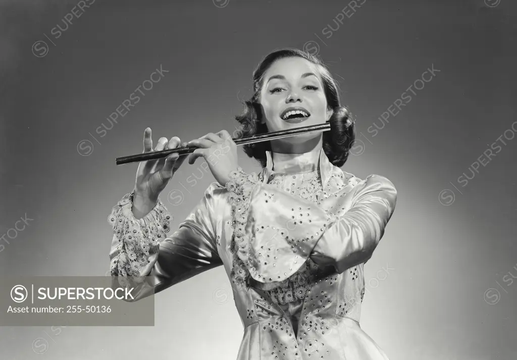 Young woman playing a flute and smiling
