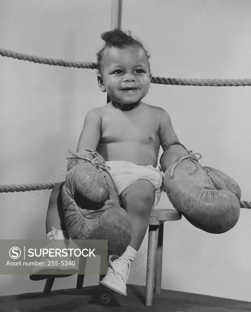 Stock Photo: 255-5340 Baby wearing boxing gloves and sitting on stool in boxing ring
