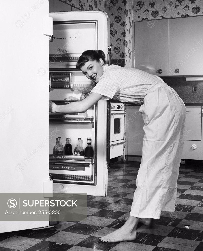 Stock Photo: 255-5355 Side profile of a young woman standing in front of a refrigerator