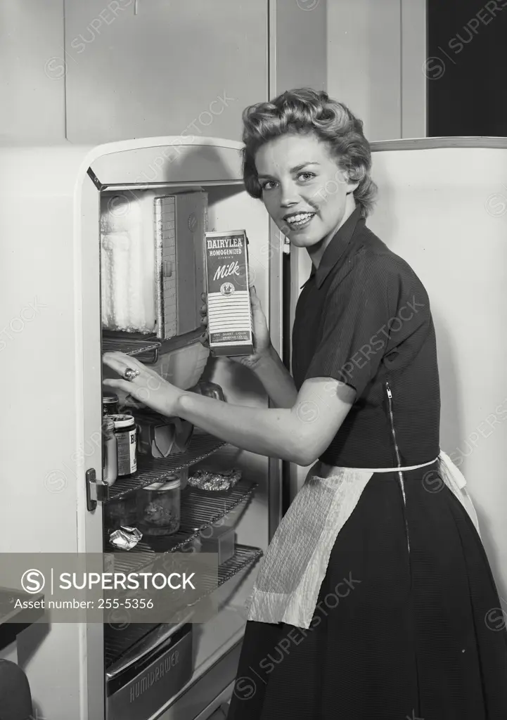 Portrait of a young woman standing near a refrigerator