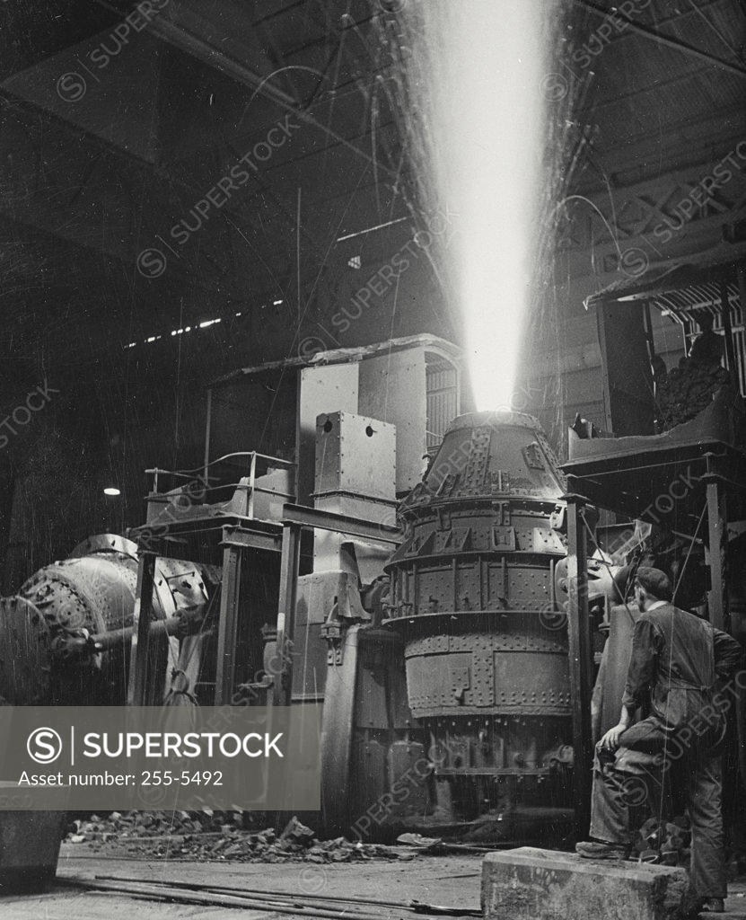 Stock Photo: 255-5492 Rear view of a mature man looking at a Bessemer converter in a steel mill