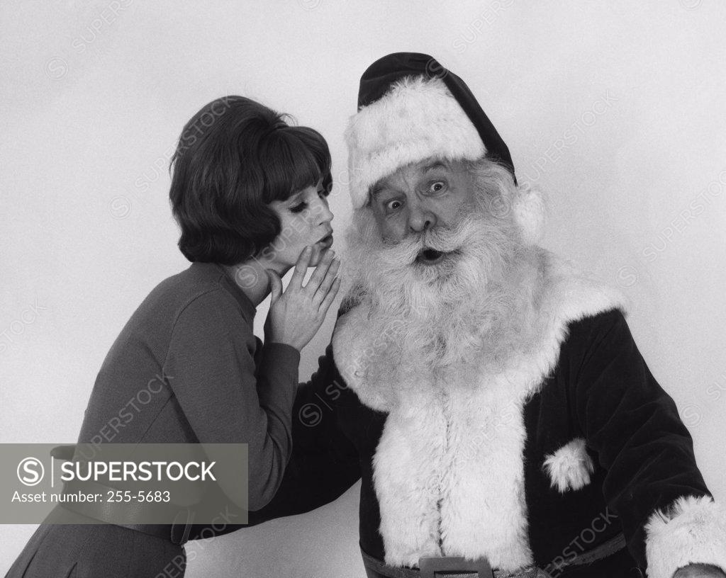 Stock Photo: 255-5683 Side profile of a young woman whispering to Santa Claus