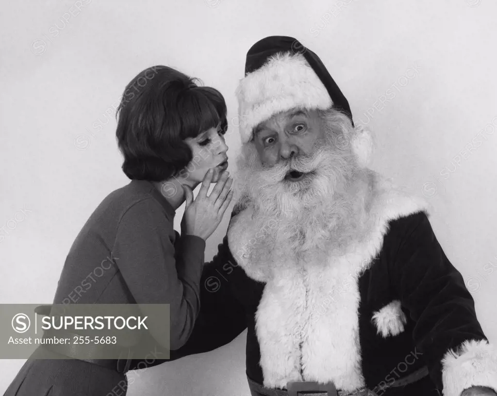 Side profile of a young woman whispering to Santa Claus