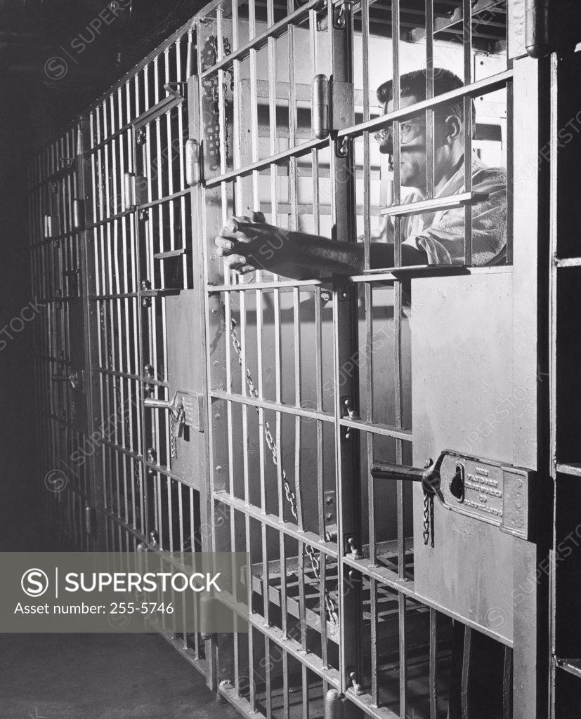 Stock Photo: 255-5746 Side profile of a male prisoner standing in a prison cell