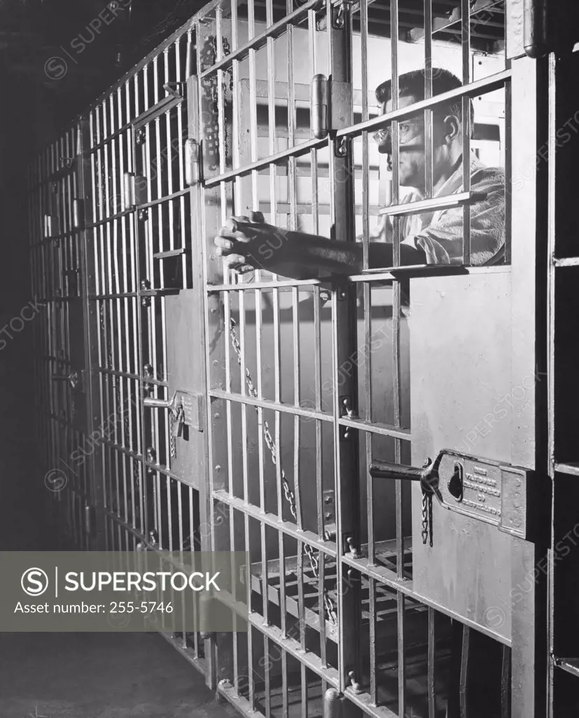 Side profile of a male prisoner standing in a prison cell