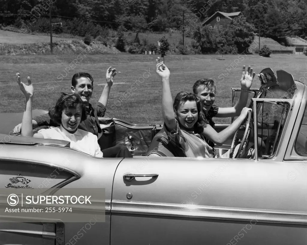 Two young couples sitting in car and waving