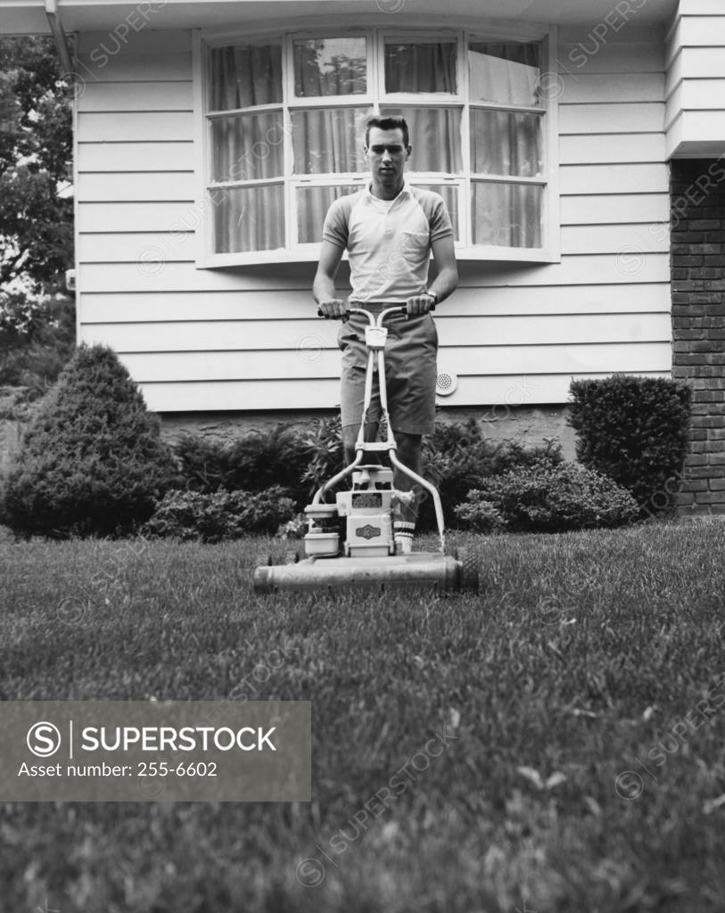 Stock Photo: 255-6602 Young man cutting grass with a lawn mower