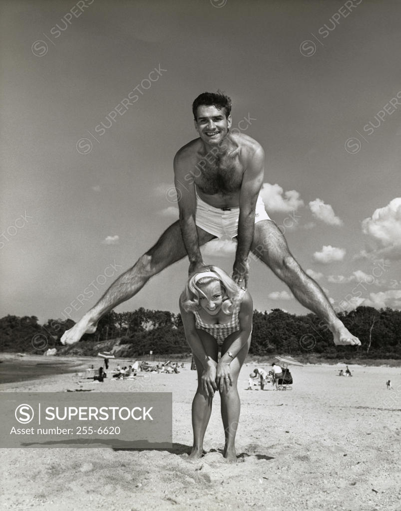 Stock Photo: 255-6620 Portrait of a young couple playing leapfrog on the beach