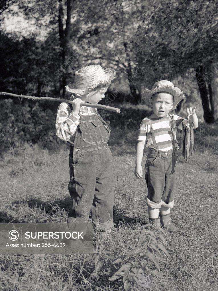 Stock Photo: 255-6629 Two boys with bunch of fish and fishing rod made of stick in field