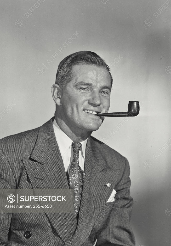Stock Photo: 255-6653 Studio portrait of smiling man with pipe
