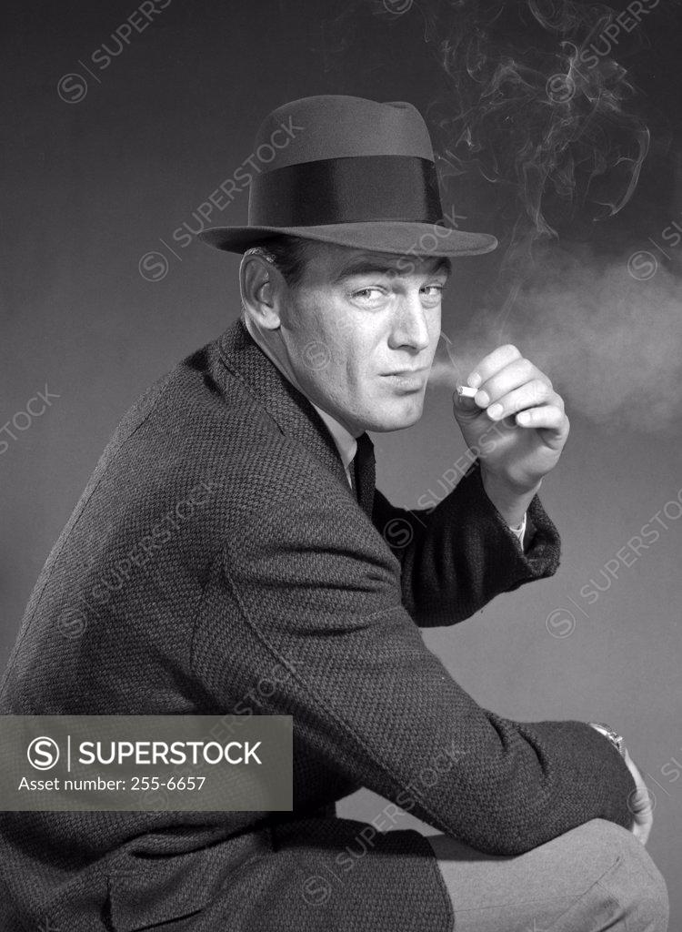 Stock Photo: 255-6657 Studio portrait of man wearing hat, smoking cigarette