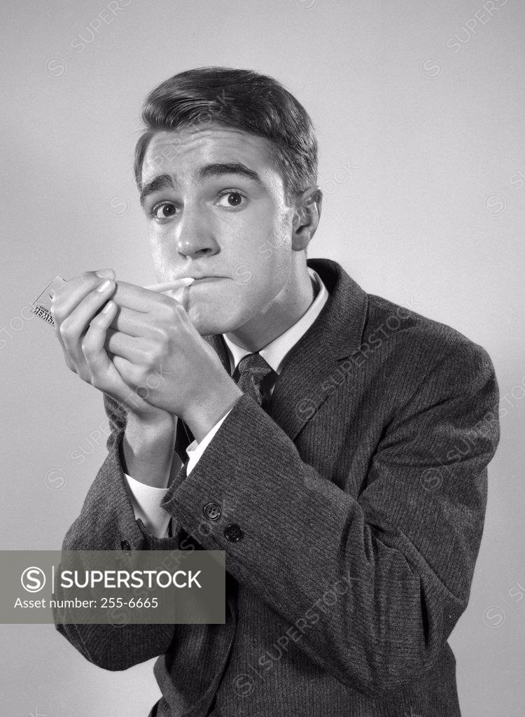 Stock Photo: 255-6665 Studio portrait of young man igniting cigarette