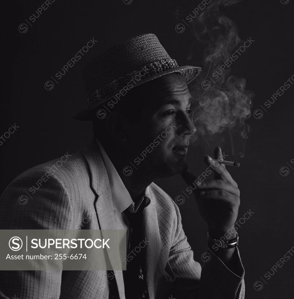 Stock Photo: 255-6674 Studio portrait of man wearing hat, smoking cigarette