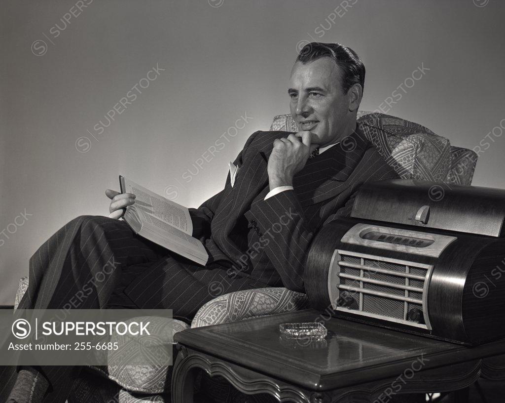 Stock Photo: 255-6685 Man with book witting on armchair
