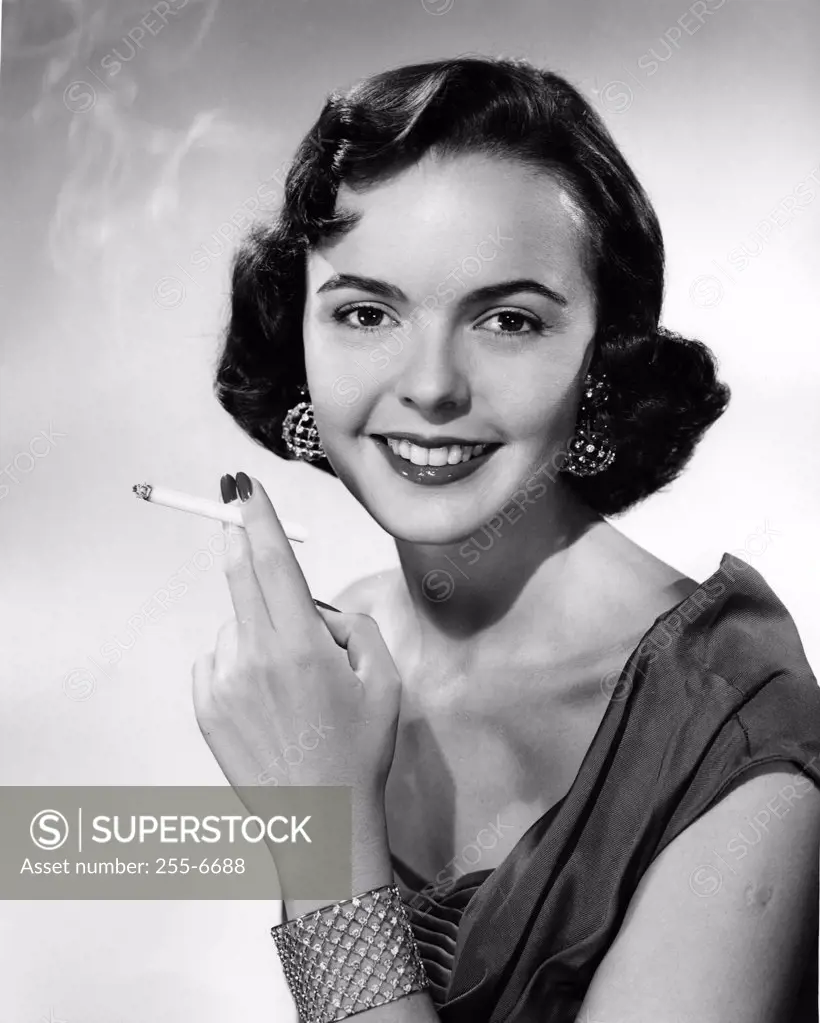 Studio portrait of smiling young woman with cigarette