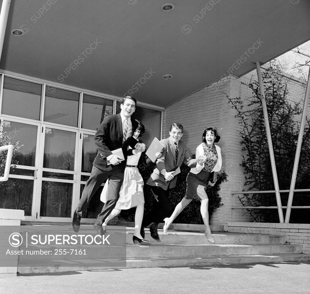 Stock Photo: 255-7161 Two young men and two young women running out of a university building