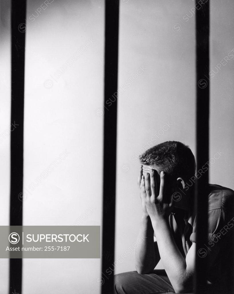 Stock Photo: 255-7187 Male prisoner sitting in prison cell